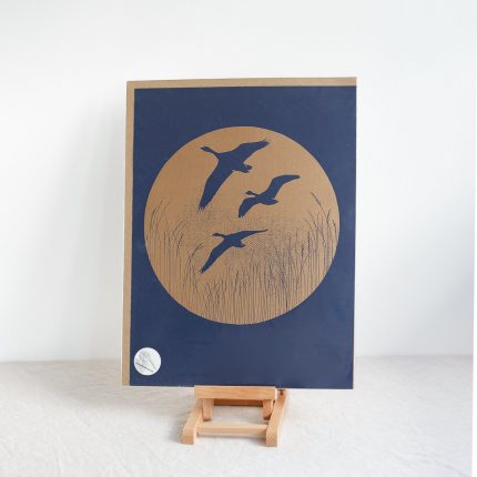 Navy print of geese flying over grass on easel