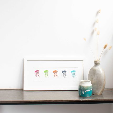 Cornish Paper Cut Art row of colourful jellyfish mounted in a white frame.