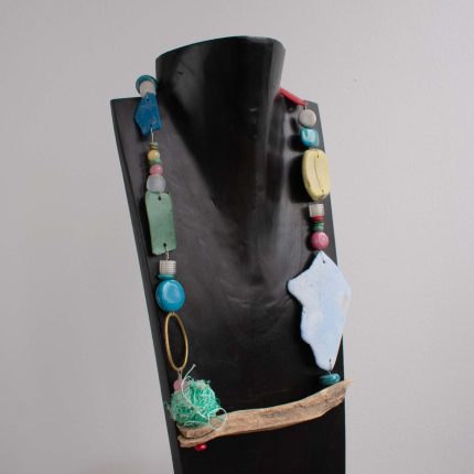 Statement necklace made of beach plastic, driftwood and brass on black bust by Sarah Drew