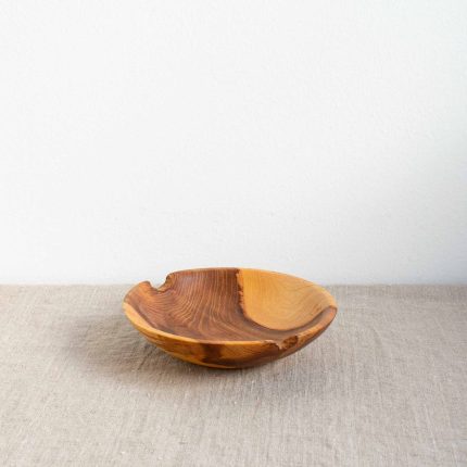 Small handcrafted wooden bowl with strong grain and natural edge chips by The Hide Studio, sitting on a linen table cloth