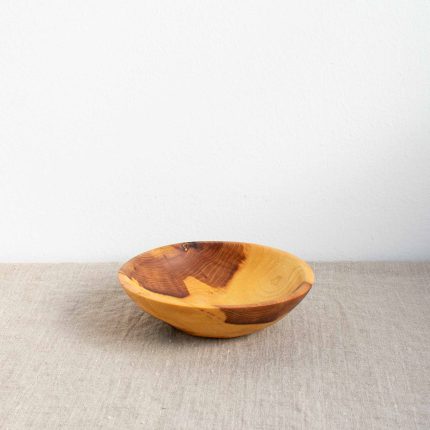 Small handcrafted wooden bowl with strong grain by The Hide Studio, sitting on a linen table cloth