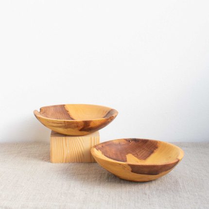 Two small handcrafted wooden bowls with strong grain by The Hide Studio, sitting on a linen table cloth