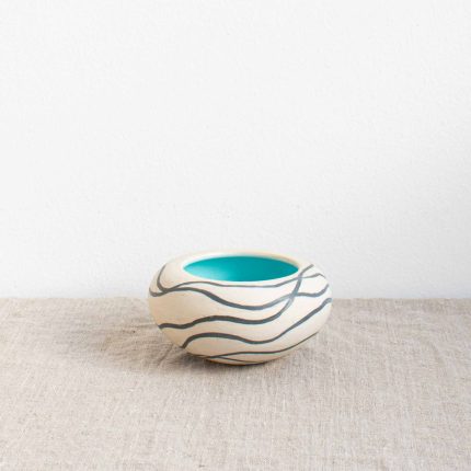 Ceramic pebble pot with matt white outside decorated with dark grey wavy lines and turquoise blue glazed inner, handcrafted by Michelle Foote, sitting on a linen table cloth