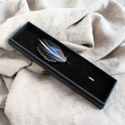 Lapel pin with blue feathers in black box on linen by Saffron & Peach