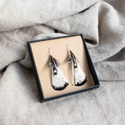 Pair of earrings made from white feathers displayed in black box on linen by Saffron & Peach