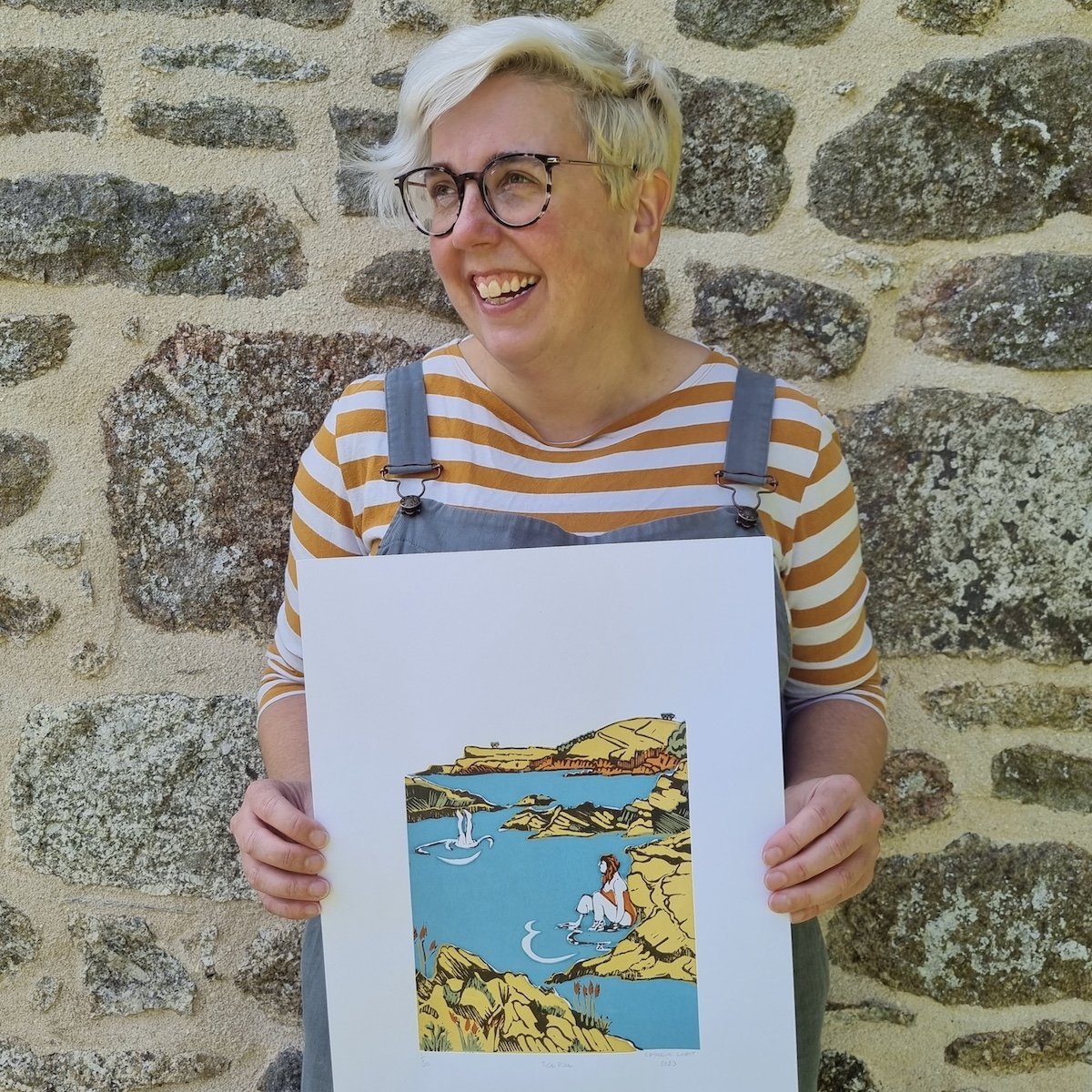 Blonde woman with glasses in striped top holding a coastal print