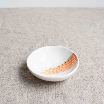 Small porcelain bowl with pink design and gold dots on a linen tablecloth by Frances Spice