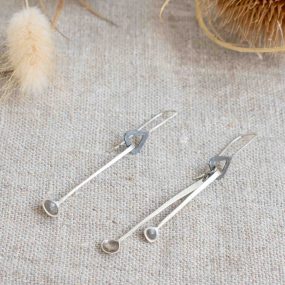 Silver Long Drop Earrings In The Shape Of Mini Spoons Handcrafted By Razmaker On A Linen Tablecloth With Teasels